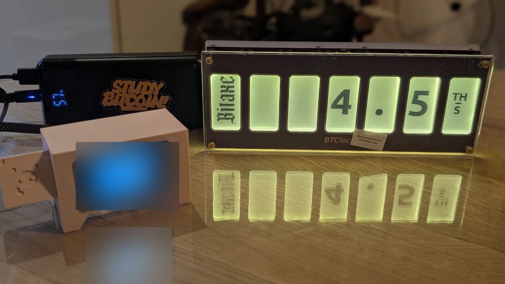 Bitcoin-Waren - https://www.bitcoinstuffstore.com BTClock mit der Hashrate eines NerdQAxe++, neben einem Lightning Piggy